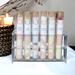 Assorted bath salts by Whole Self Aromatherapy in test tubes on elegant white linen, with a candle softly glowing in the background.